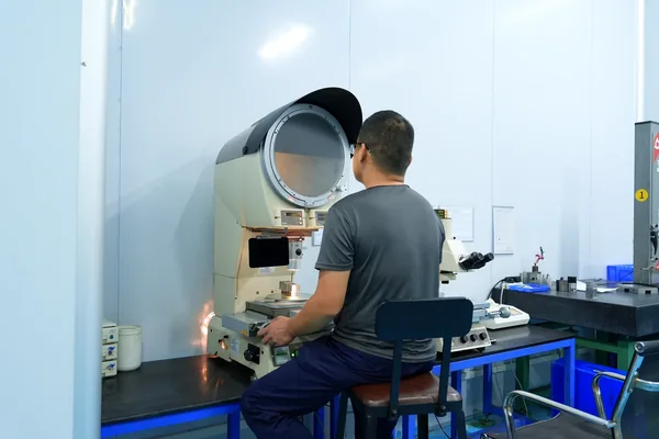 Optical Profile Projector Inspection Operator inspecting a component with an optical profile projector